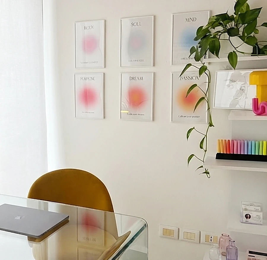 La scrivania di vetro nello studio, con le stampe colorate alle pareti